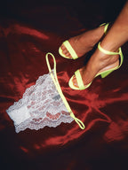 white lace thong with neon trim and matching neon shoes against a red velvet backdrop